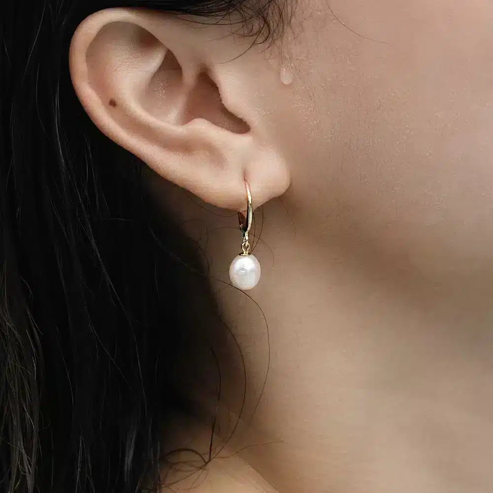 women wearing Luxe Golden Hoop Pearl Earrings featuring gold-plated 925 silver hoops with dangling white freshwater pearls