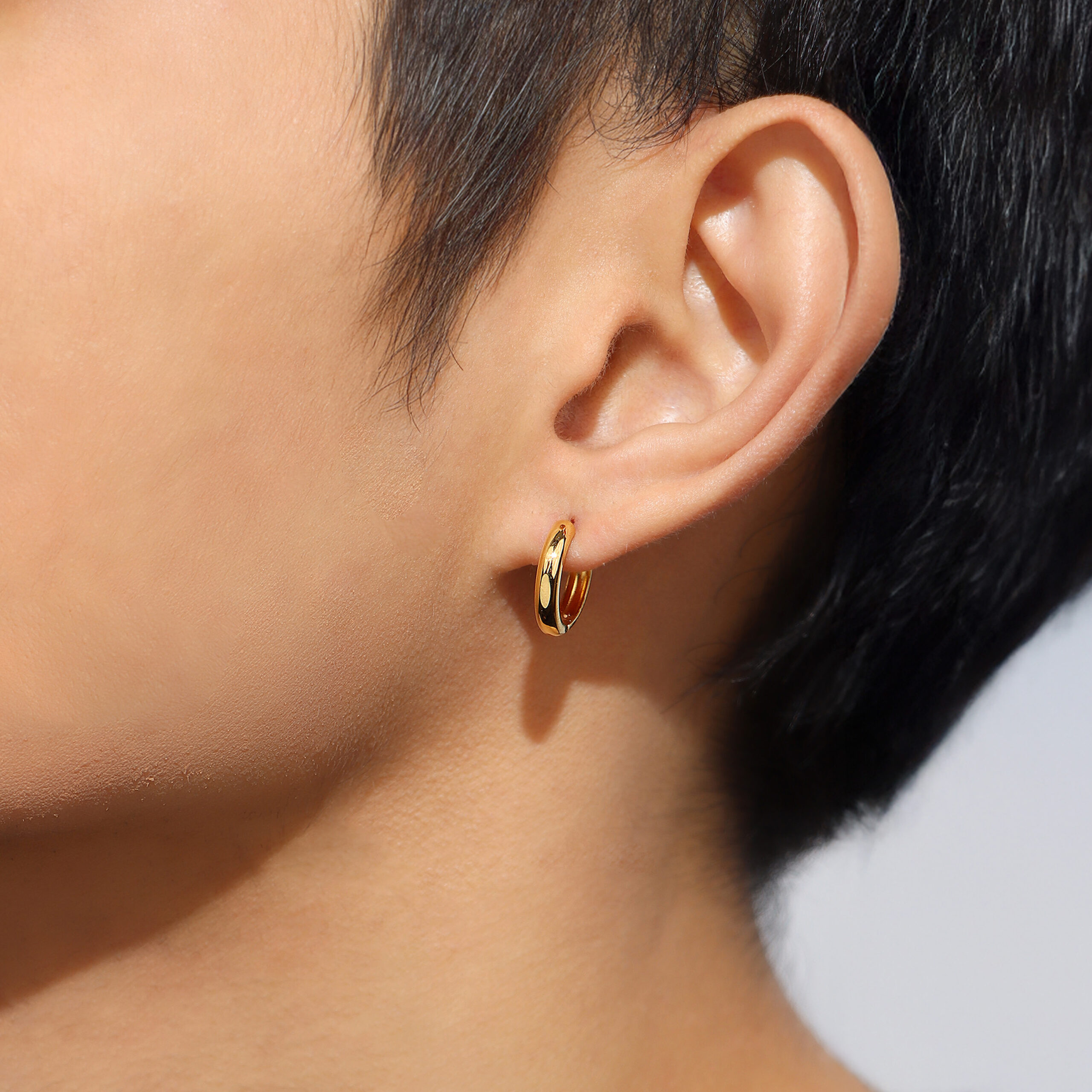 women wearing SK 916 Bold Rounded Hoop Gold Earrings in yellow gold, featuring a sleek and thick rounded hoop design crafted from 916 gold