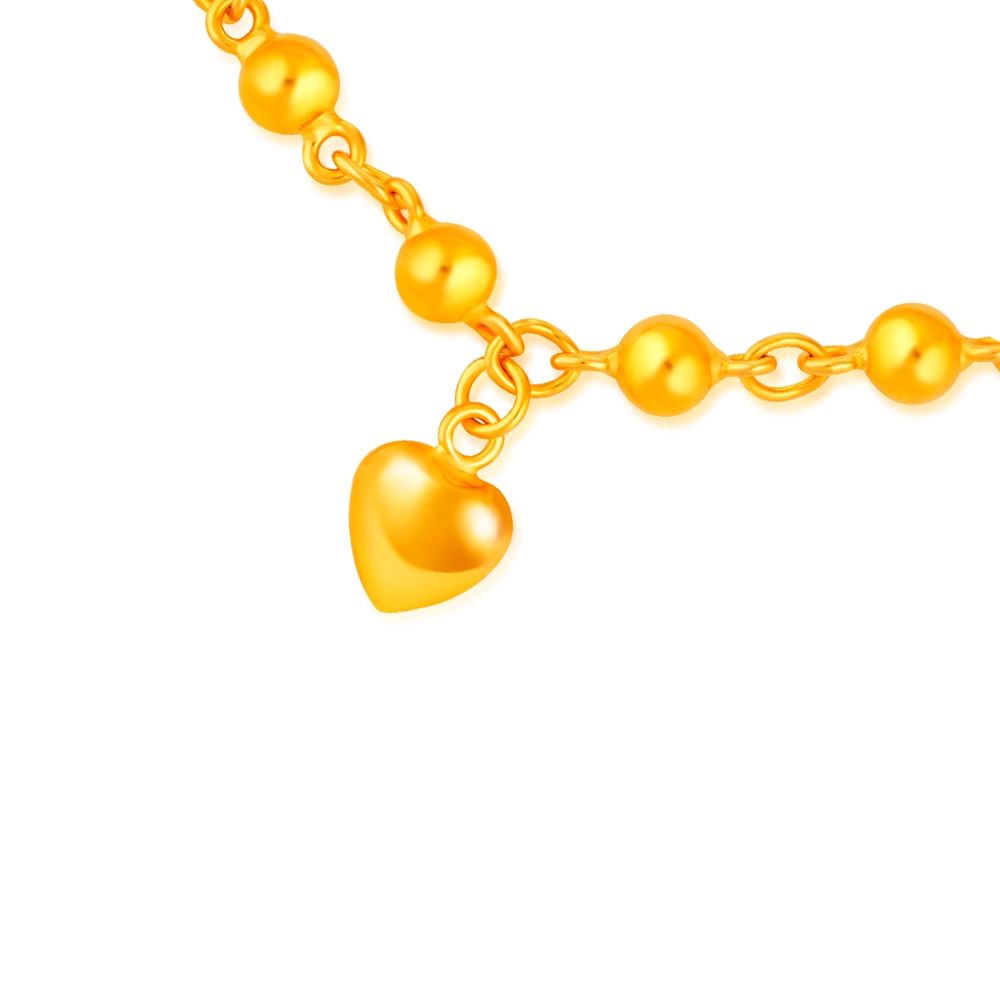 SK BRACELET FOR WOMEN BUBBLE HEART close up of the dangling heart charm in 916 gold